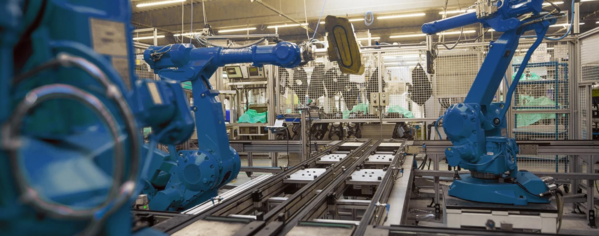 Een foto van een productielijn met daaraan verschillende blauwe robots die het werk verrichten